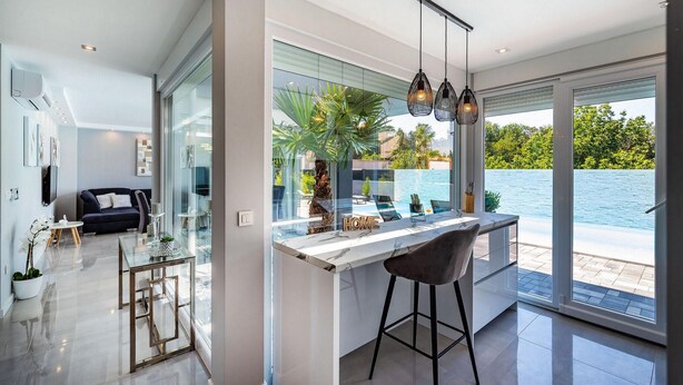 Eine moderne Küche mit großem Fenster, Blick auf einen Pool und das Meer.