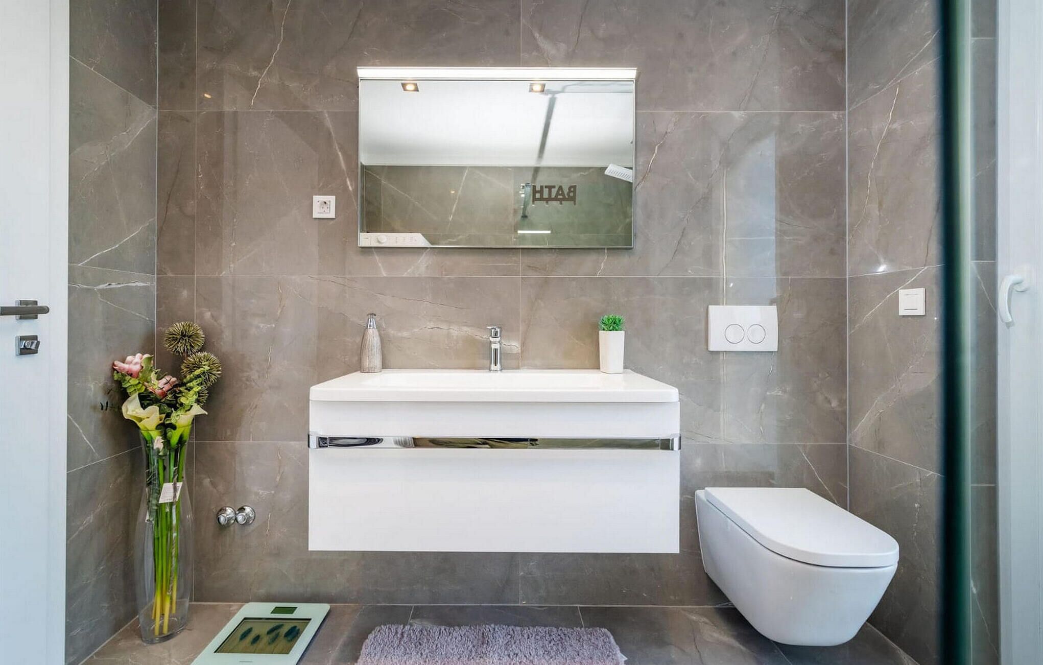 A modern bathroom with a white vanity, a toilet, and a shower area.
