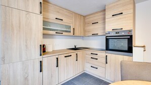 Eine moderne Küche mit hellen Holzschränken, einem eingebauten Backofen und einer schwarzen Arbeitsplatte.