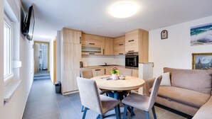 Eine moderne Küche mit Holzschränken, einem Esstisch mit vier Stühlen und einem Kühlschrank.