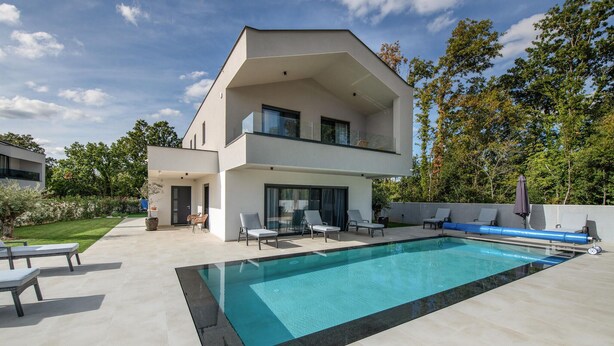 Ein modernes, zweistöckiges Haus mit Swimmingpool, Sitzgelegenheiten im Freien und einem gepflegten Garten.