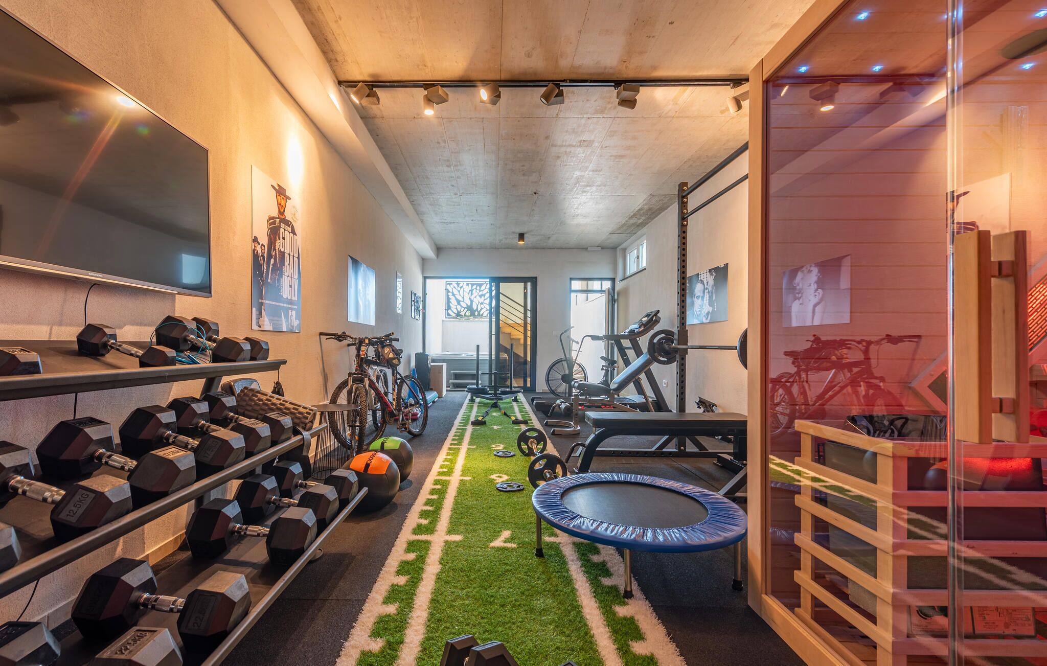A gym with exercise equipment, a trampoline, and a TV on the wall.