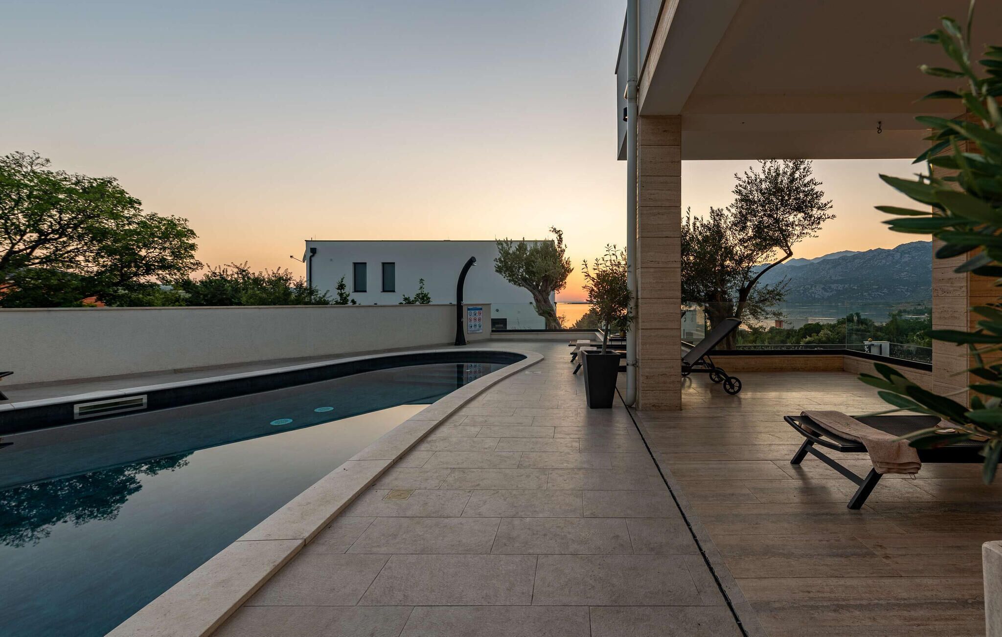 Un espace piscine sur le toit offrant une vue sur une montagne et le coucher de soleil.