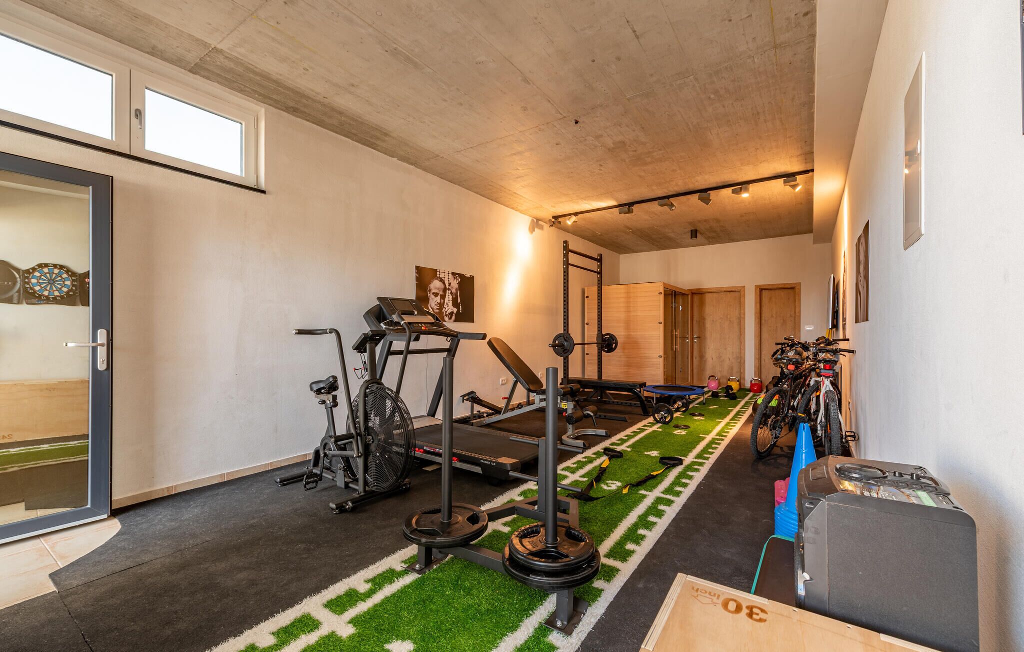 Une salle de sport à domicile équipée de matériel d’exercice, d’un tapis de course, de poids et d’un tapis de yoga.