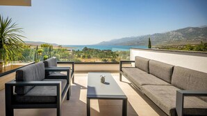 A terrace with a sofa, chairs, and a table overlooking a scenic view of the sea and mountains. - Stunning home in Rovanjska with sauna (Rovanjska)