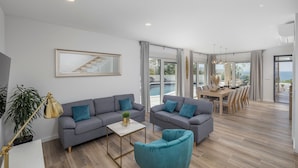 A spacious living area with a grey sofa set, a small coffee table, and a teal armchair. A dining area with a wooden table and chairs is visible in the background. - Stunning home in Rovanjska with sauna (Rovanjska)
