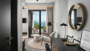A modern hotel room with a large window offering a view of the sea, a round mirror, a desk with a lamp, and a framed motivational quote. - Luxurious home in Crni (Crni)