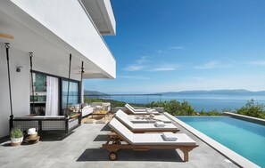 A modern outdoor pool area with lounge chairs and a view of the sea. - Luxurious home in Crni (Crni)