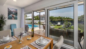 Ein Essbereich mit Tisch für vier Personen, mit Blick auf Pool und Garten.