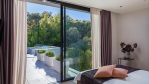 A modern bedroom with a large bed, a view of a balcony with plants, and a glass door leading to an outdoor area. - Lovely home in Pakostane (Pakostane)