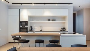 A modern kitchen with white cabinetry, a wooden island, and black chairs. - Lovely home in Pakostane (Pakostane)