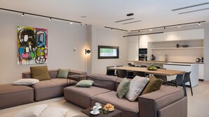 A modern living room with a sectional sofa, a coffee table with pastries, and a vibrant abstract painting on the wall. - Lovely home in Pakostane (Pakostane)