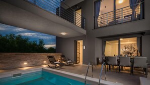A modern outdoor pool area with lounge chairs and a dining table. - Cozy home in Privlaka with sauna (Privlaka)