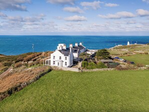 Ein Küstenhaus mit Meerblick und einem Leuchtturm im Hintergrund.