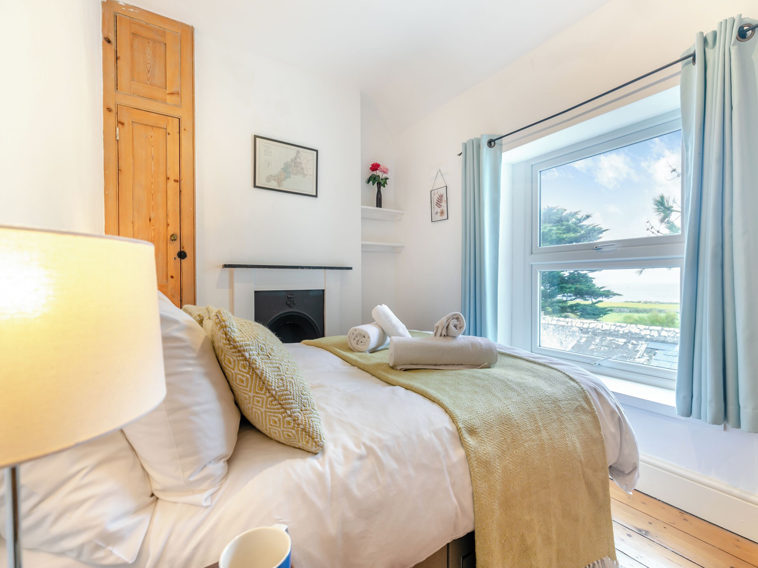 Un dormitorio con cama, lámpara, chimenea, ventana con cortinas y un mapa en la pared.