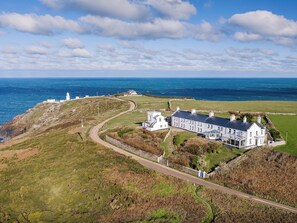 A coastal property with a large white building, a lighthouse, and a winding road.