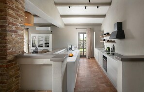 A modern kitchen with a brick wall, white cabinetry, and a stone backsplash. - Beautiful home in Sv. Lovrec (Sv. Lovrec)