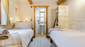 A bedroom with two beds, a wooden ceiling, a window, and a bathroom visible through an open door. - 2 bedroom accommodation in Foxhole, near Beauly (Foxhole, near Beauly)