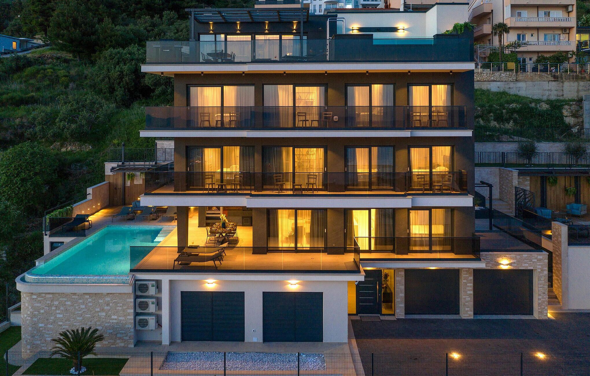Une maison moderne à plusieurs étages, dotée d’une piscine, de balcons et d’un intérieur bien éclairé.