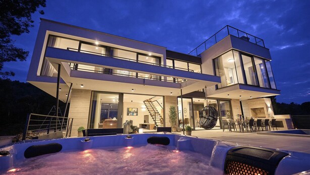 Una casa moderna de dos pisos con un jacuzzi al frente.