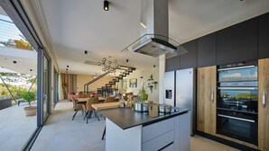 Una cocina moderna con una isla central, electrodomésticos integrados y vistas al exterior.