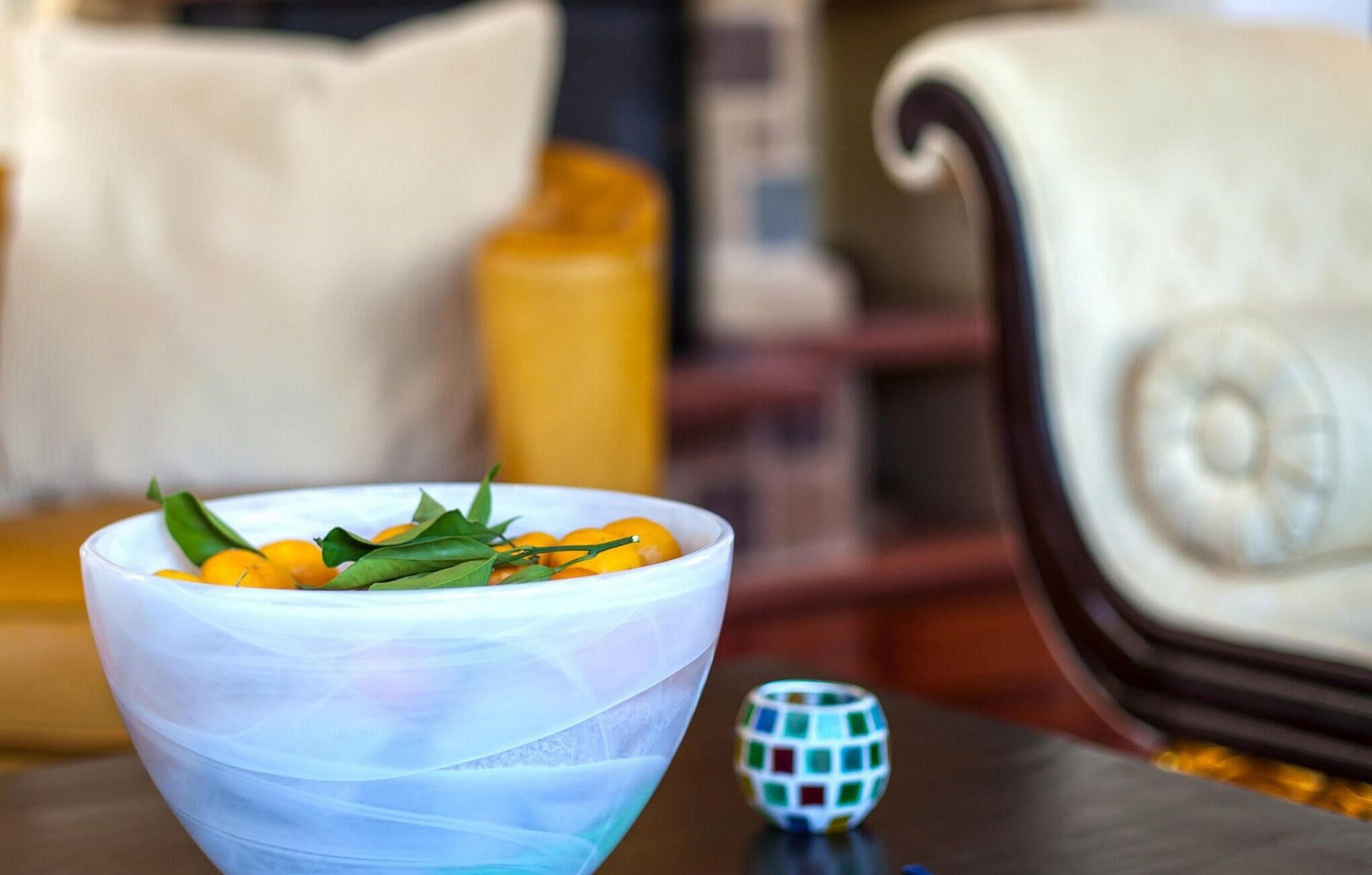 A bowl of fruit with a decorative item on a table.