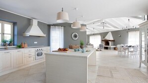 A modern kitchen with a central island, white cabinetry, and pendant lighting. - Luxurious home in Bajkini (Bajkini)