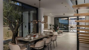 A modern dining area with a long table, chairs, and a chandelier. - Gorgeous home in Petrcane (Petrcane)