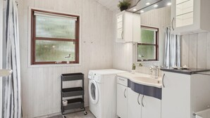 A compact bathroom with a washing machine, a sink, and cabinets. - Cozy home in Hjørring with WiFi (Hjørring)