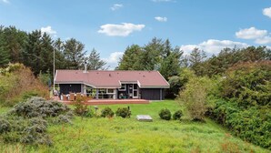 A house with a red-tiled roof, a covered patio, and a well-maintained lawn. - Cozy home in Hjørring with WiFi (Hjørring)