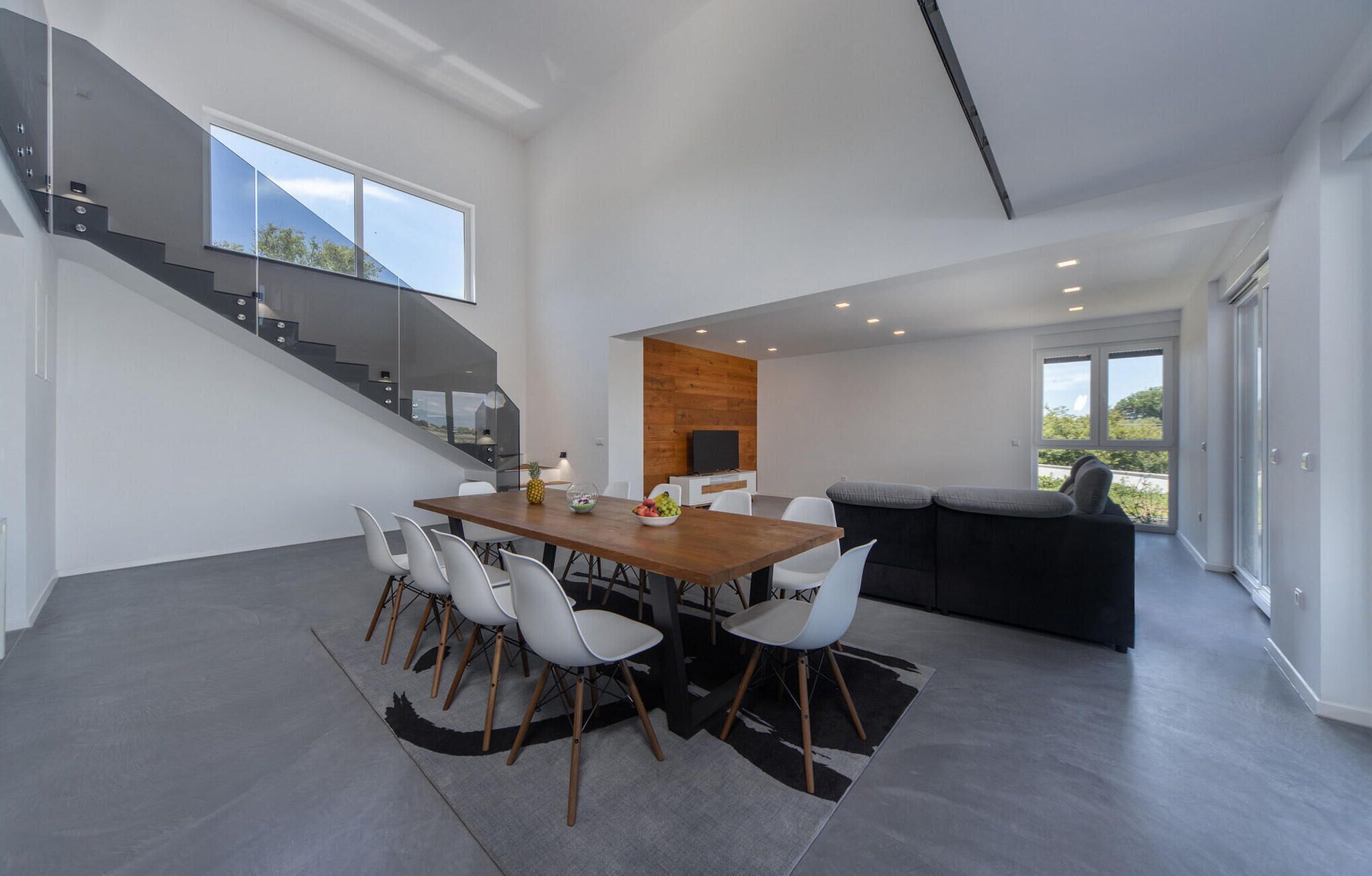A modern interior with a dining area, a sofa, and a staircase.