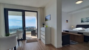 A modern hotel room with a balcony, a bed, a desk, and a chair.