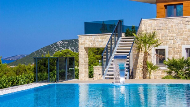 A modern house with a stone facade, a glass staircase, and a swimming pool.
