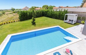 A rectangular swimming pool with a clear blue tile finish, surrounded by a well-maintained lawn and a hedge. - Gorgeous home in Zemunik Donji (Zemunik Donji)