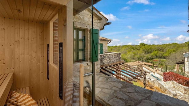 Ein Zimmer aus Holz mit einer Steinwand und Blick auf einen angelegten Garten.