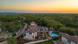 Eine Villa mit Swimmingpool, umgeben von üppiger Vegetation und freiem Blick auf die Landschaft.