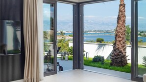 A room with a large sliding glass door leading to a balcony with a view of a lake and mountains. - Beautiful home in Nin (Nin)