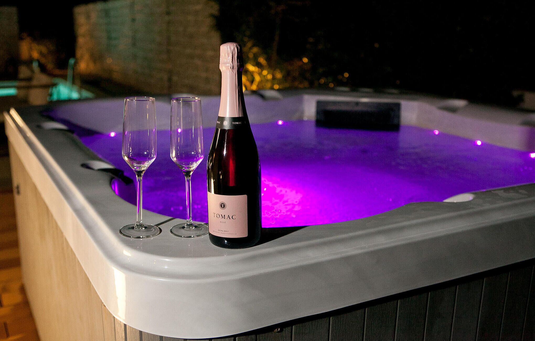 Un jacuzzi con una botella de vino y dos copas.