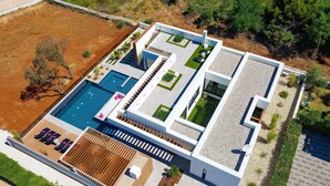 Une maison moderne dotée d’une piscine, d’un espace salon extérieur et d’un jardin bien entretenu.