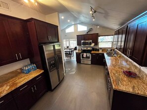 A modern kitchen with dark wood cabinets, stainless steel appliances, granite countertops, and a central island. - Boulders Views, patio, quiet neighborhood with no additional taxes (West Hills)