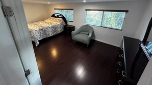 Un dormitorio con cama, una silla, un escritorio y televisión.