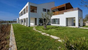 Ein modernes, zweistöckiges Haus mit Flachdach, großen Fenstern und einem Steinweg, der zum Eingang führt.