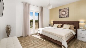 Ein Schlafzimmer mit einem großen Bett, Blick ins Freie und einem modernen Kronleuchter.