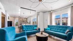 Ein großzügiges Wohnzimmer mit zwei blauen Sofas, einem Couchtisch und einer modernen Deckenleuchte.