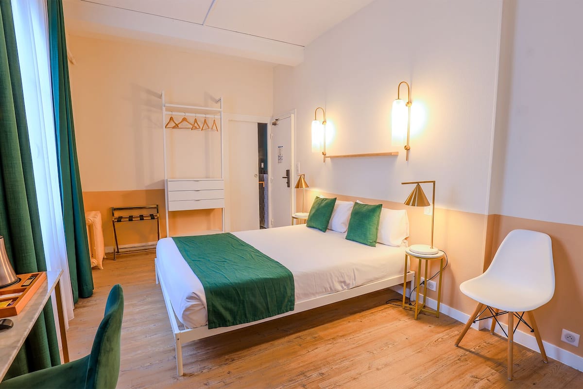 Une chambre d’hôtel comprenant un lit, une table de chevet, une chaise et une armoire.