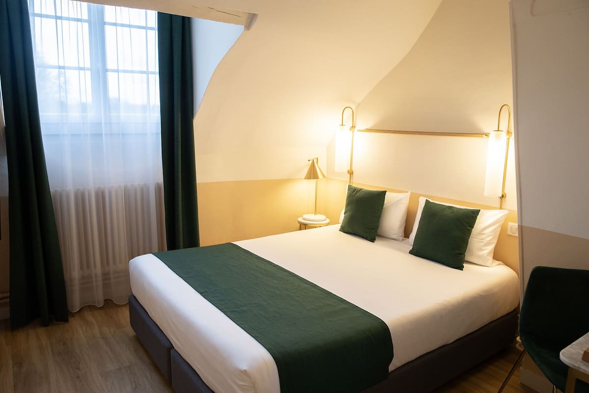 Une chambre d’hôtel avec un lit, une table de chevet, une lampe et une chaise.