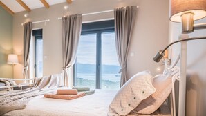 A bedroom with a bed, a bedside table, a lamp, and a view of the outdoors through large windows. - Beautiful home in Suzan (Suzan)