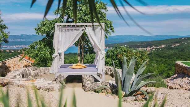 A secluded outdoor bed with a white canopy, surrounded by rocks and plants, overlooking a scenic landscape with mountains and a village. - Beautiful home in Suzan (Suzan)