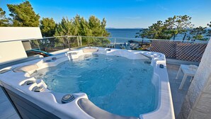 Ein Whirlpool mit freiem Blick auf das Meer und Bäume im Hintergrund.