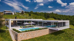 Une maison moderne dotée d’une piscine, de grandes baies vitrées et d’un mur de soutènement en pierre.
